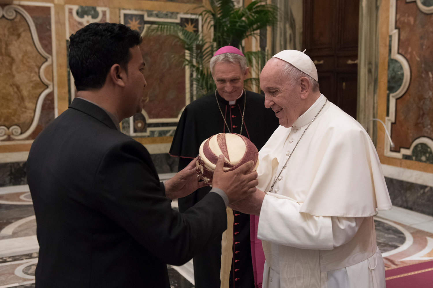 Pope Francis is presented with a turban during a meeting April 26, 2019, at the Vatican with members of the Catholic Biblical Federation. At center is Archbishop Georg Ganswein, prefect of the papal household.